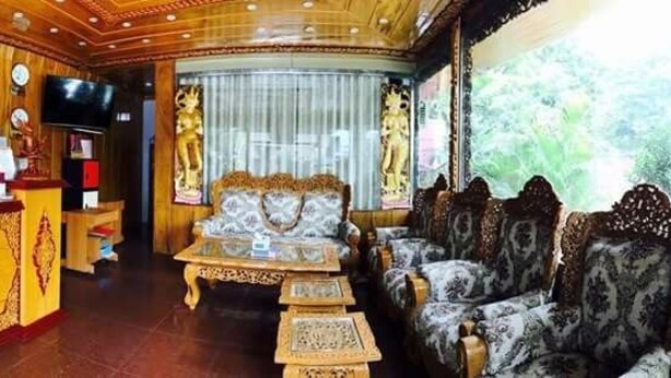 A traditional interior with a reception desk, ornate sofas, and a large window providing a view of greenery. - Nan Htike Yadanar Hotel (Monywa)