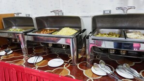 A buffet setup with various food items in stainless steel containers, arranged on a patterned table with a red border. - Nan Htike Yadanar Hotel (Monywa)