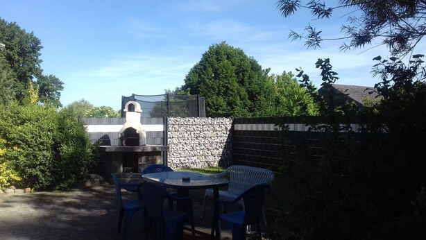 Un patio al aire libre con un muro de piedra, una mesa redonda y sillas de plástico azules.