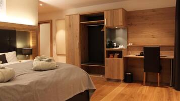 A modern hotel room with a large bed, a desk, and a wardrobe.
