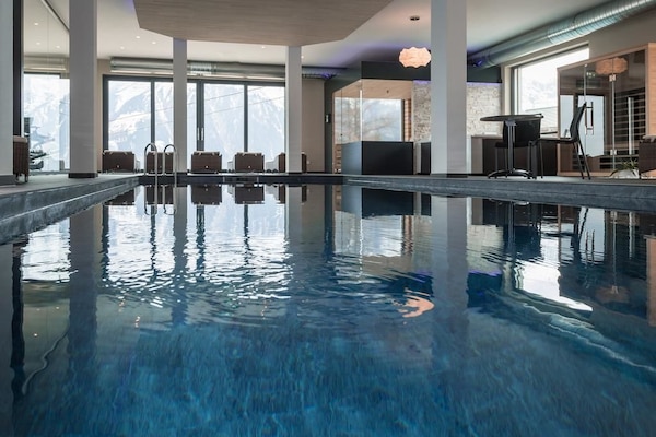 Una piscina techada, sillones reclinables de piscina