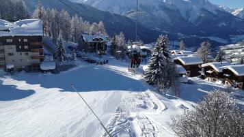 A ski resort with snow-covered buildings, a ski lift, and mountains in the background.
