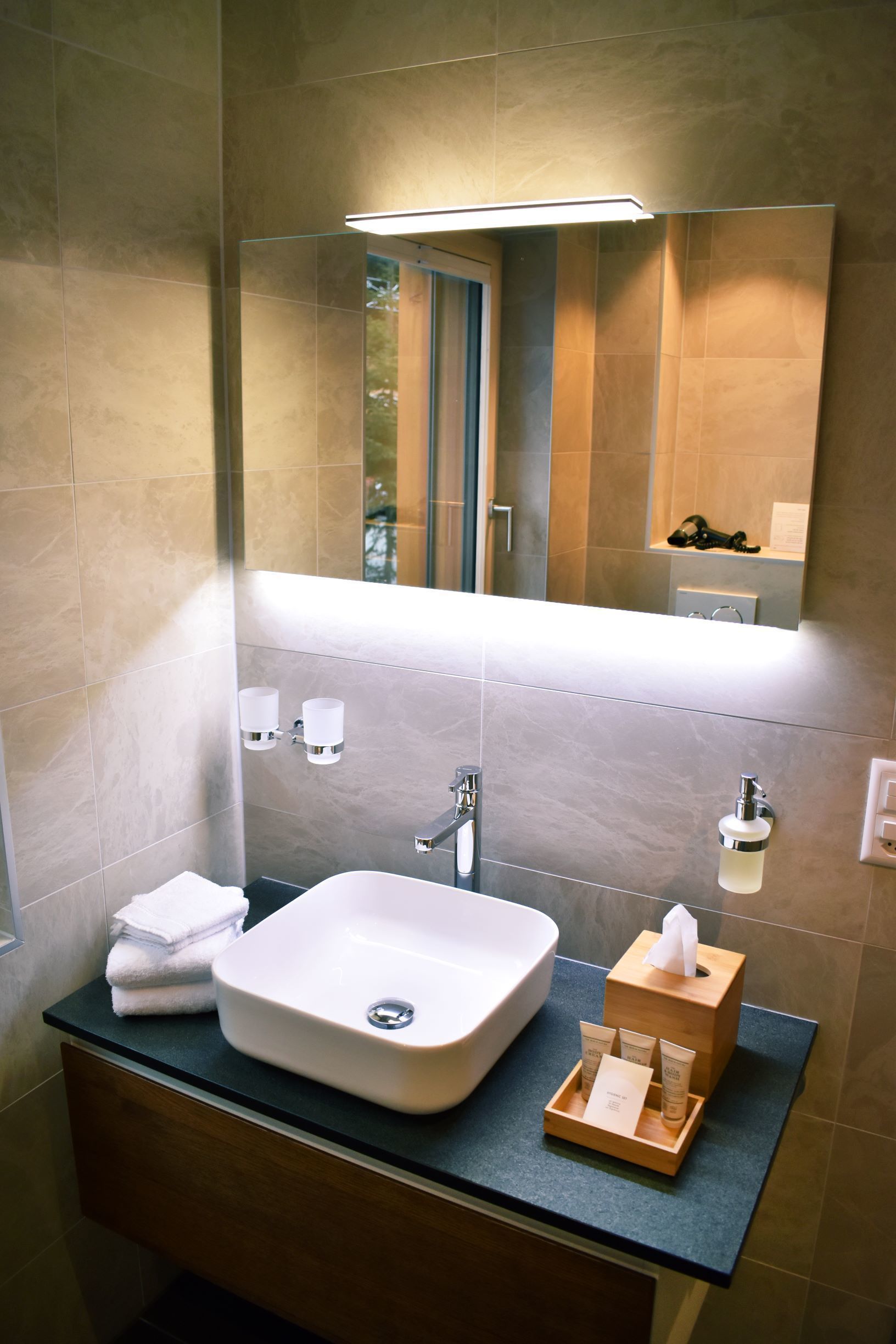 Un baño moderno con un espejo grande, un lavabo blanco y un mueble de tocador de madera.