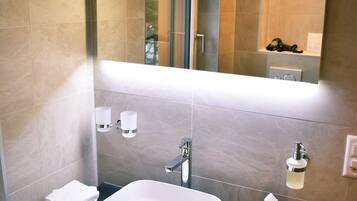 Un baño moderno con un espejo grande, un lavabo blanco y un mueble de tocador de madera.