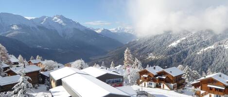 A snow-covered mountain village with wooden cabins and a ski lift.