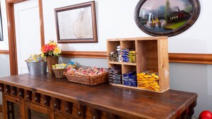 A wooden table with baskets of snacks, a framed certificate, and a wooden shelf with packaged goods. - Rialto Hotel (Laredo)