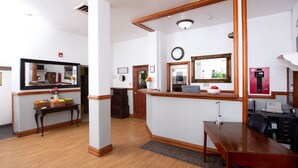A spacious room with a wooden floor, a desk, a chair, a large mirror, and a small table with baskets. - Rialto Hotel (Laredo)