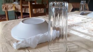 A dining table with a white plate, a clear glass, and a napkin.