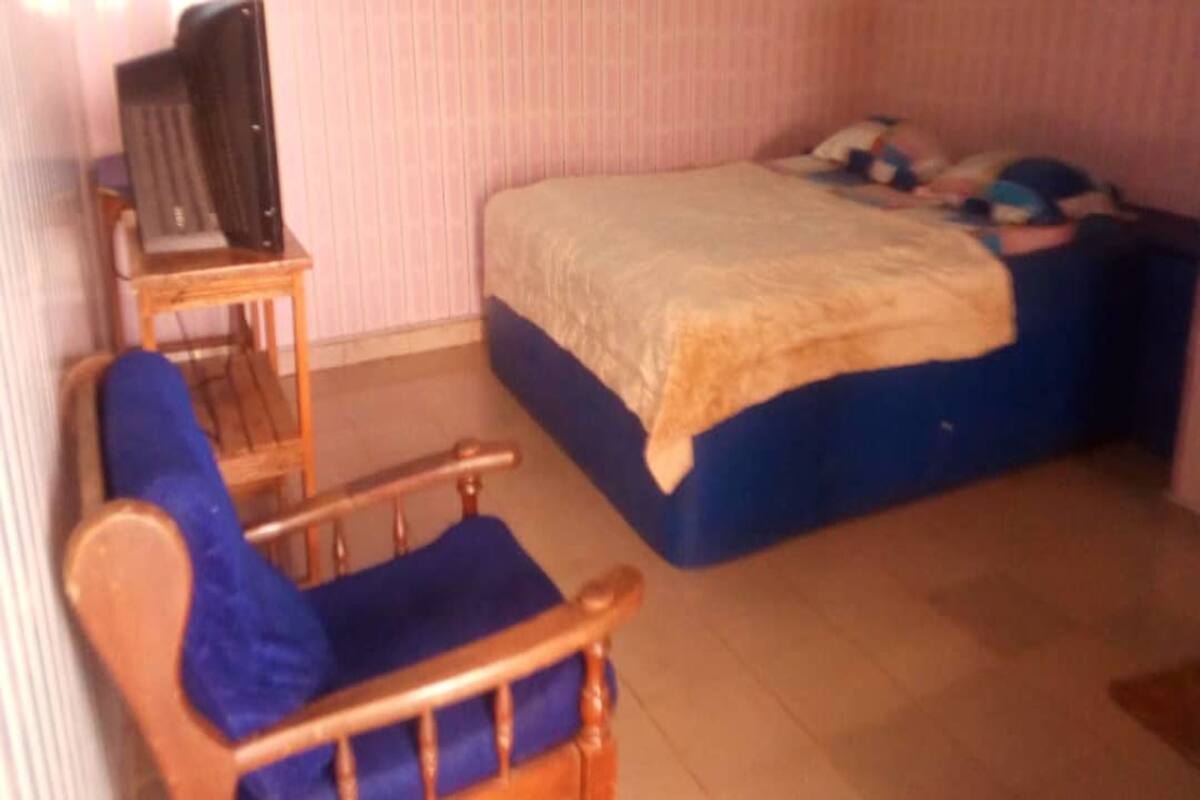 Un dormitorio con una cama, una silla de madera y una mesita.
