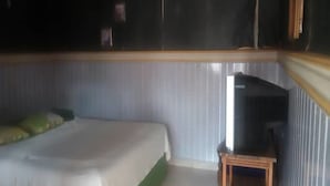 Ein Schlafzimmer mit einem Bett, einem kleinen Holztisch und einem Fernseher.
