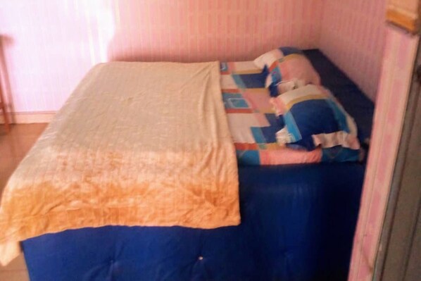 Una habitación pequeña con una cama individual, un colchón azul y una colcha acolchada.