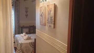 A hallway with a bed, a lamp, and artwork on the wall.