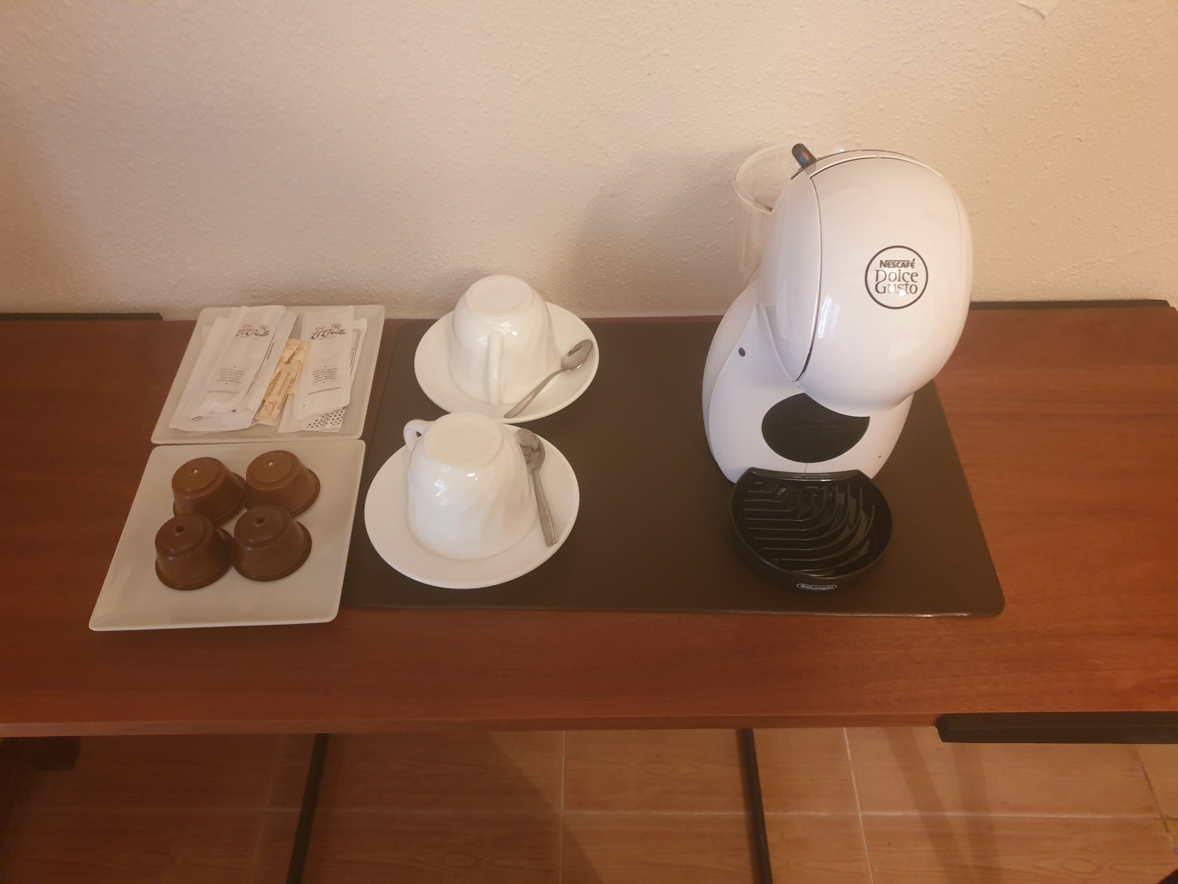 Een tafel met een koffiezetapparaat, een bord koekjes en een kop koffie.