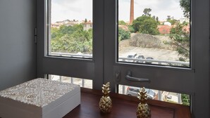 Una habitación con un amplio ventanal, una caja decorativa blanca y dos pequeñas macetas con plantas sobre una mesa de madera.