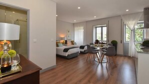 Una habitación de hotel moderna con comedor, ventanas amplias y kitchenette.