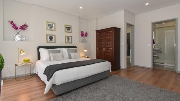 Un dormitorio moderno con una cama grande, mesitas de noche, un armario y decoración en la pared.