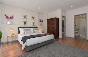 A modern bedroom with a large bed, bedside tables, a wardrobe, and wall-mounted decor. - Rosario's Boutique Apartments (Porto)