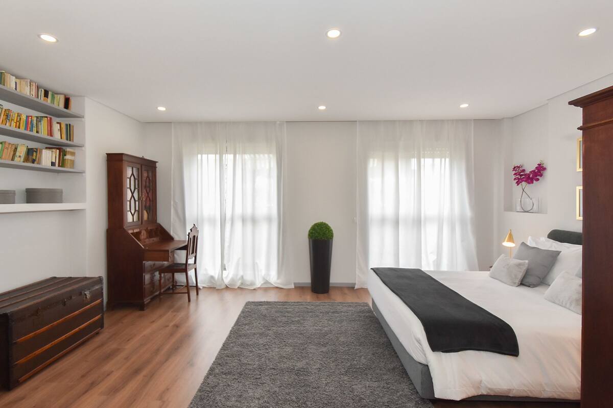 Un dormitorio con cama, escritorio, estantería y planta en maceta.