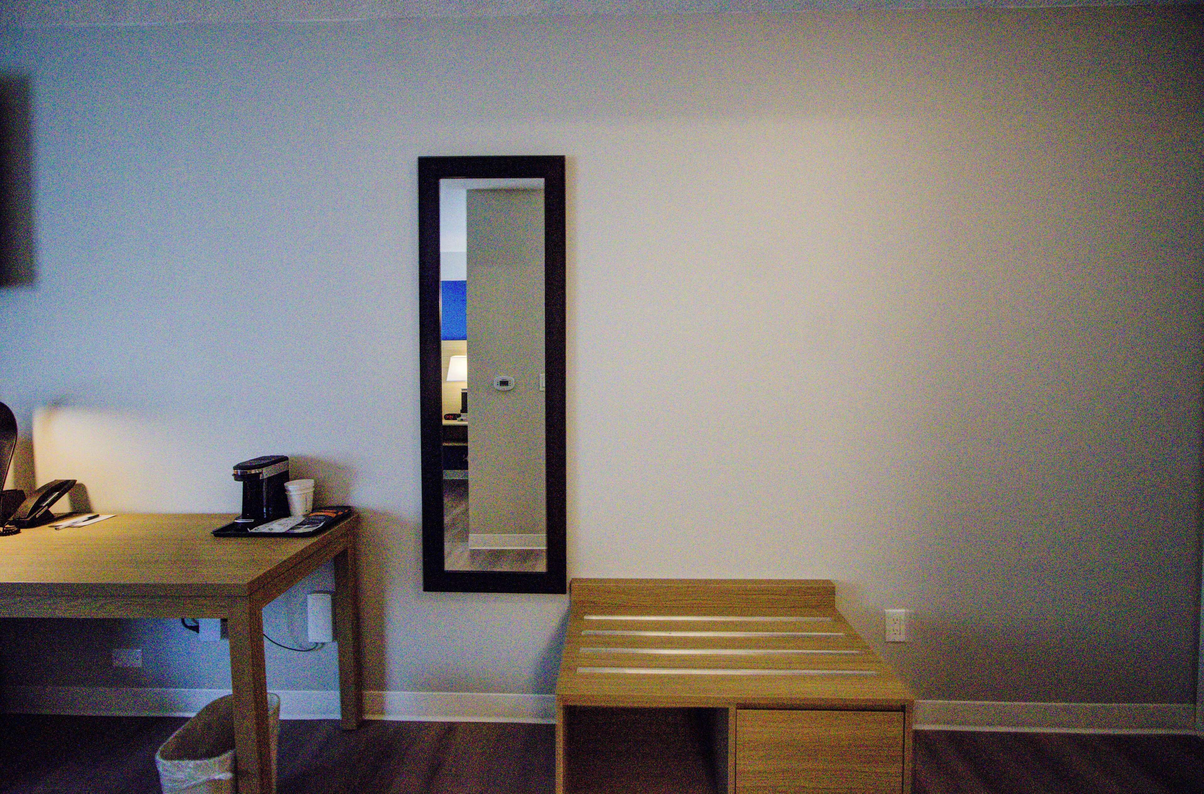 A room with a wooden desk, a mirror, and a small bench.
