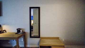 A room with a wooden desk, a mirror, and a small bench.