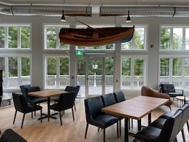 Un amplio espacio interior con ventanas grandes, mesas de madera y sillas de cuero negro.