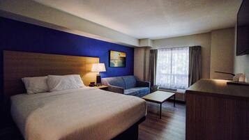 A hotel room with a large bed, a sofa, a desk, and a TV.