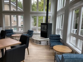 Un amplio espacio interior con ventanas grandes, una chimenea y un mobiliario moderno.