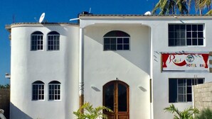 Un edificio de dos pisos con una entrada central, ventanas amplias y un cartel que dice "Regi Hotel Bar".