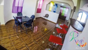 Una zona de comedor con una mesa y sillas, una barra con taburetes rojos y una escalera que sube a otro nivel.