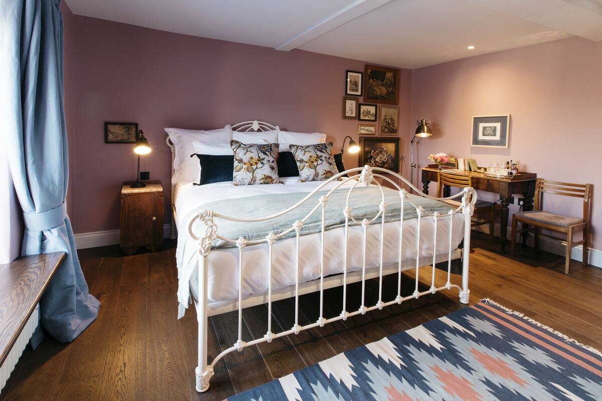 Une chambre à coucher avec un lit en métal, un plancher en bois et un bureau avec une chaise.