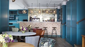Eine Bar mit einer Theke, Hockstühlen und einer Auswahl an Flaschen und Gläsern.