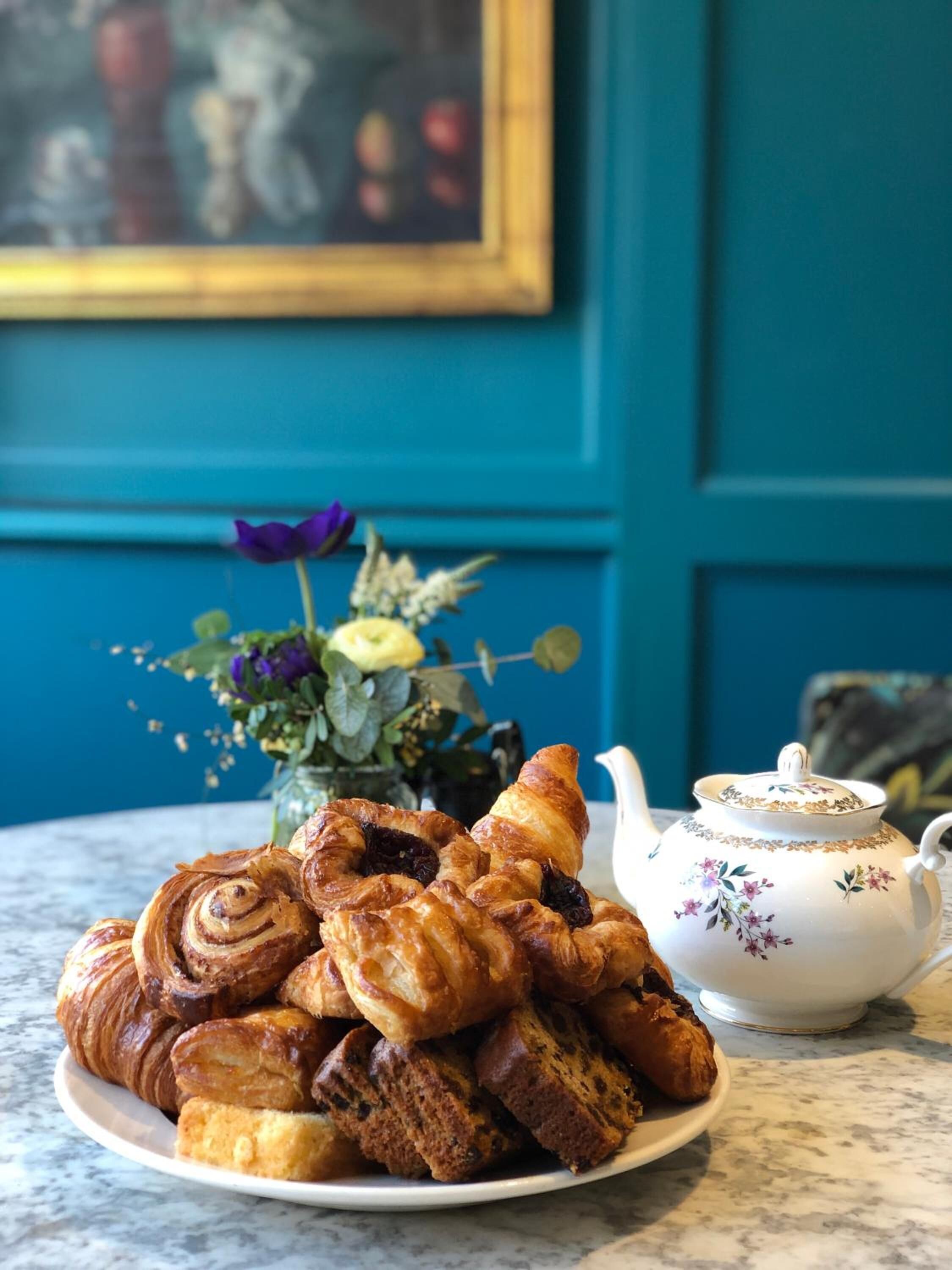 A plate of pastries and a teapot on a table.