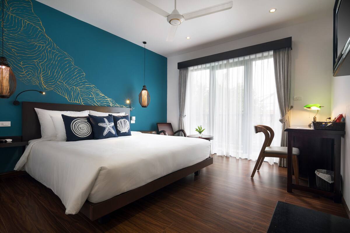 A modern hotel room with a large bed, a desk, and a chair.