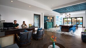 A modern hotel lobby with a reception desk, seating area, and a view of the pool. - The Blue Alcove (Da Nang)
