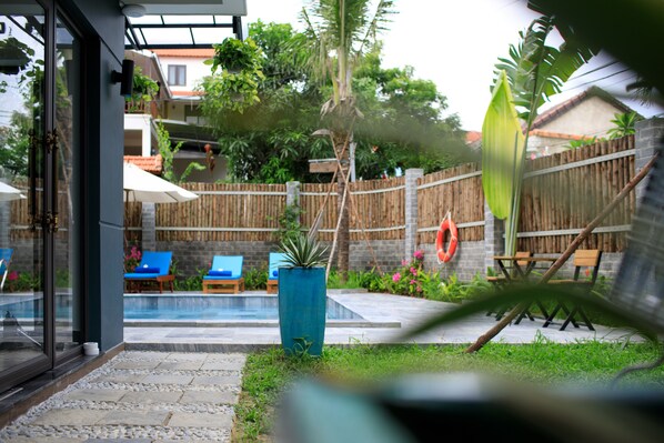 A backyard with a swimming pool, lounge chairs, and a wooden fence.