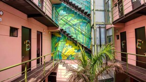 Un atrio de varios niveles con una escalera, plantas de palma y un mural vibrante.