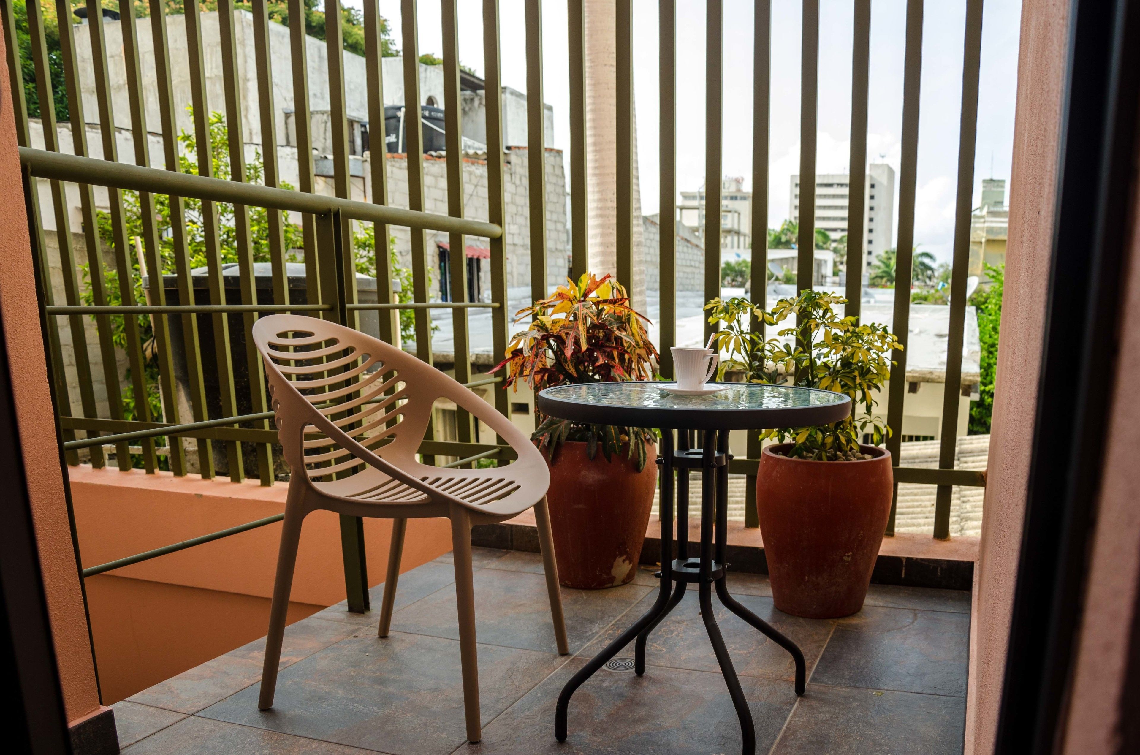A balcony with a chair, a small table, and two potted plants.