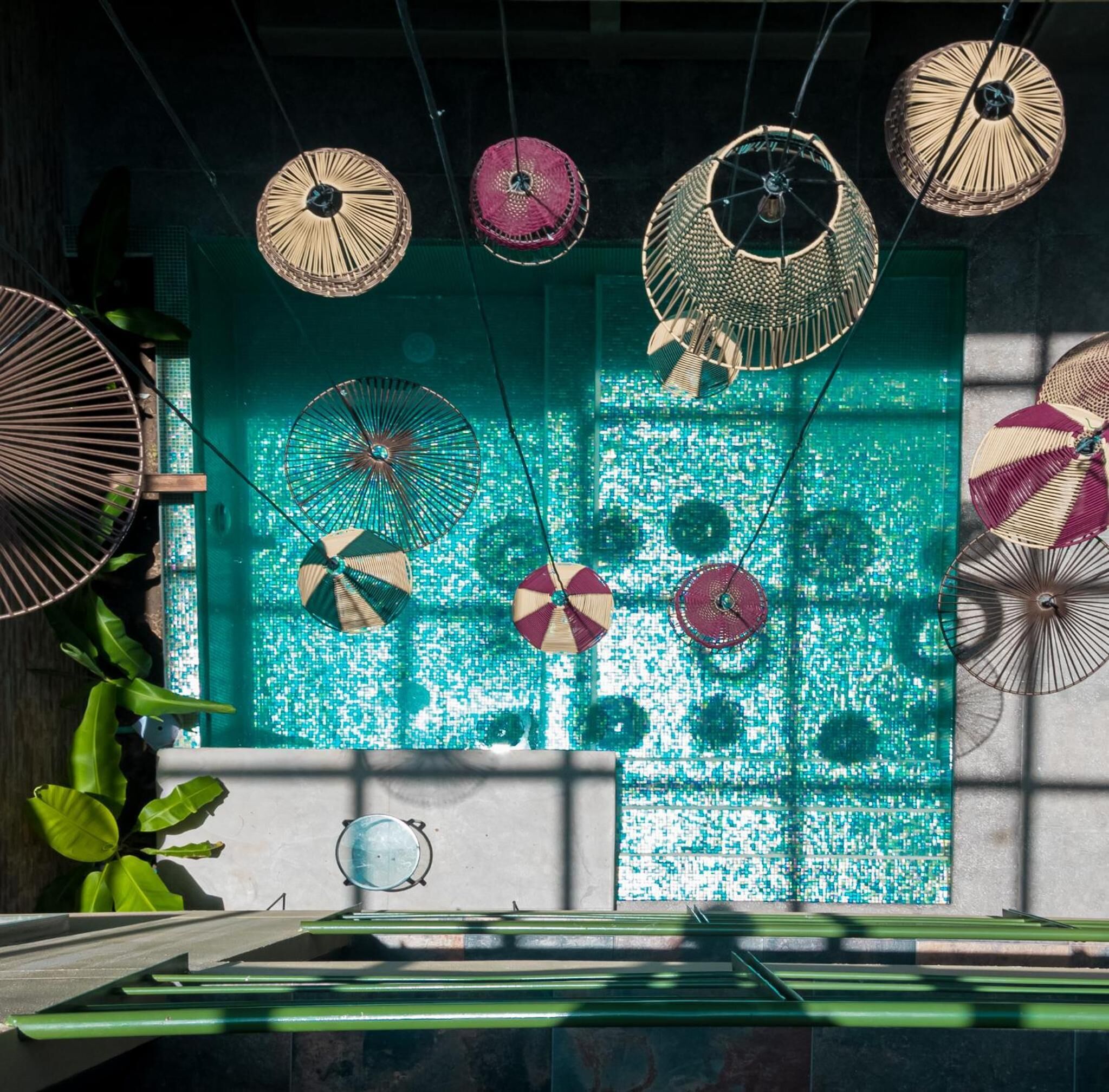 A room with a mosaic wall, hanging fans, and a green bench.