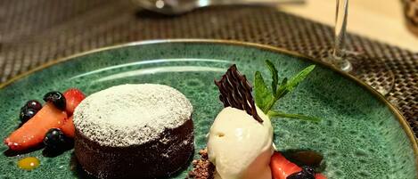 A dessert plate with a chocolate cake, ice cream, and fresh berries, accompanied by a glass of white wine.