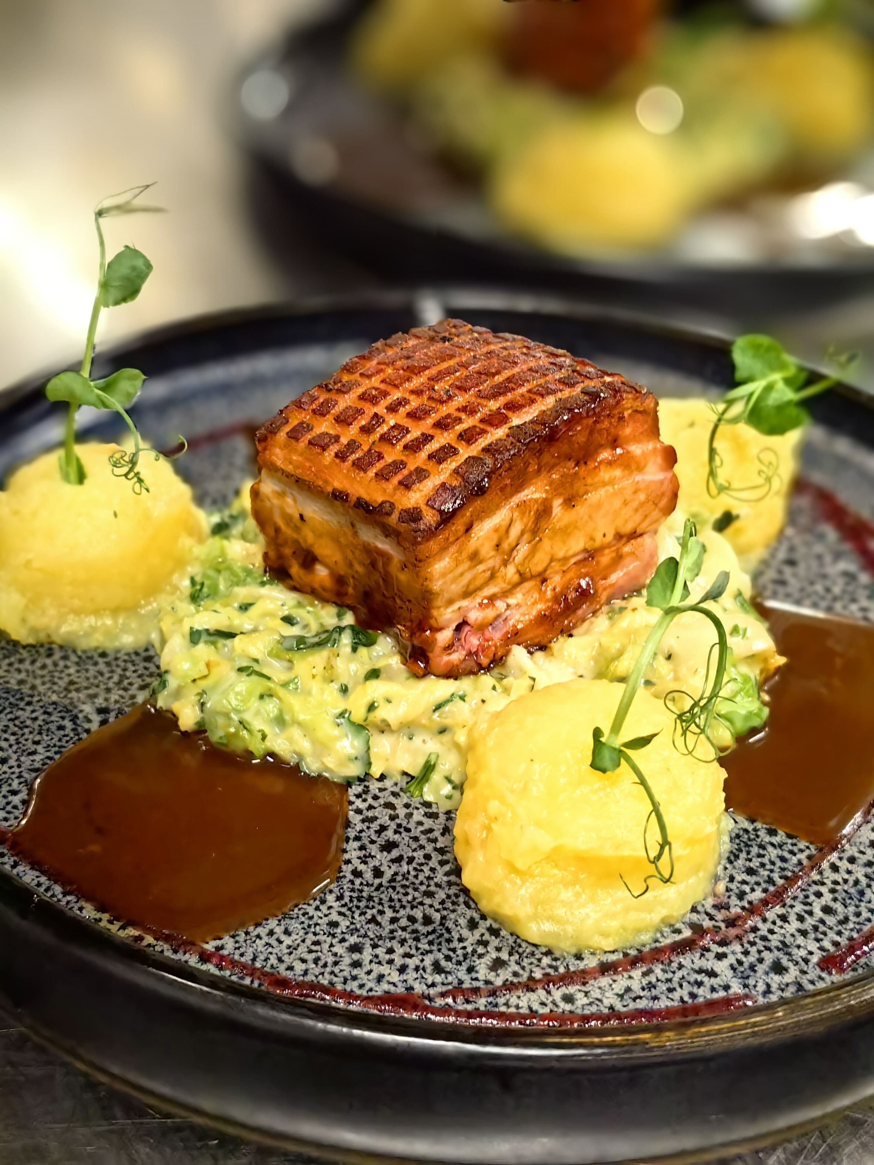 A plate with a grilled meat, mashed potatoes, and a sauce.