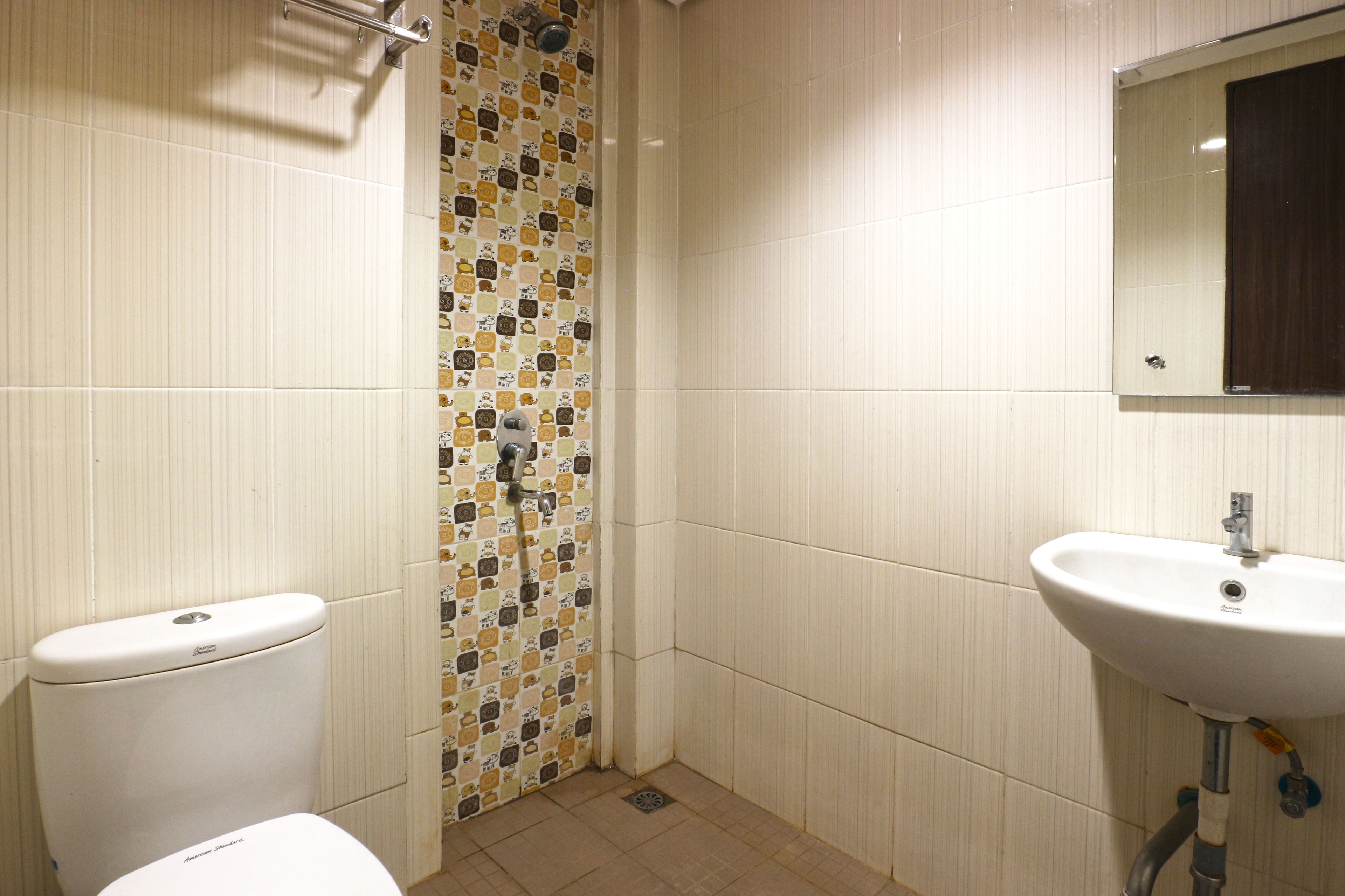 Un baño con inodoro, ducha con cortina estampada y lavabo con espejo encima.
