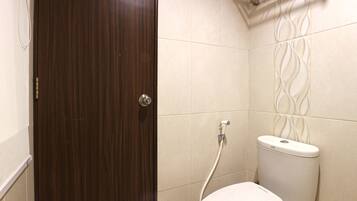 A bathroom with a wooden door, a white toilet, and beige tiled walls.