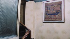 A staircase with a wooden handrail, a patterned wall, and a framed artwork depicting a building scene. - King Stone Hotel (South Tangerang)