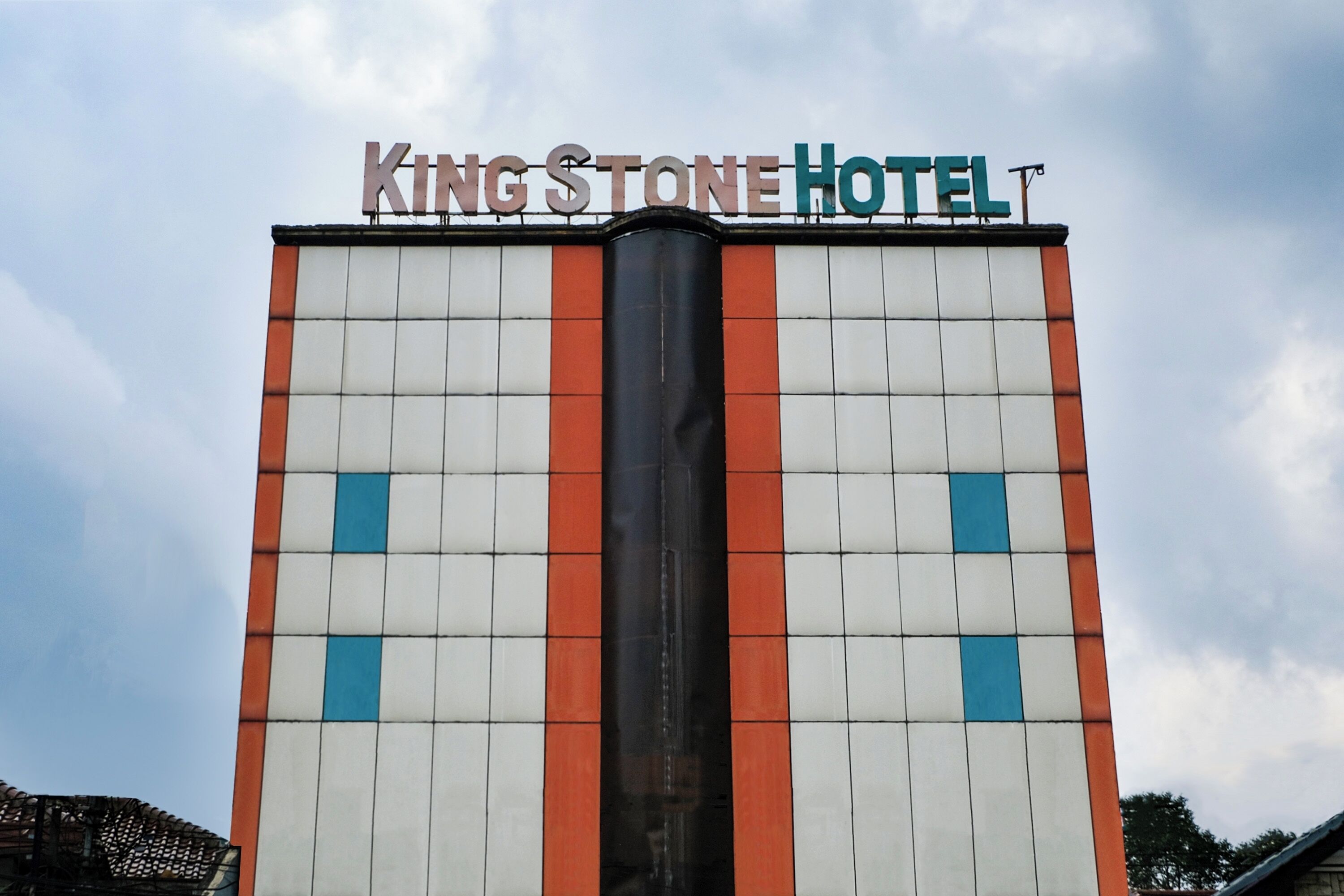 Une enseigne d’hôtel portant le nom « King Stone Hotel », sur fond de ciel nuageux.