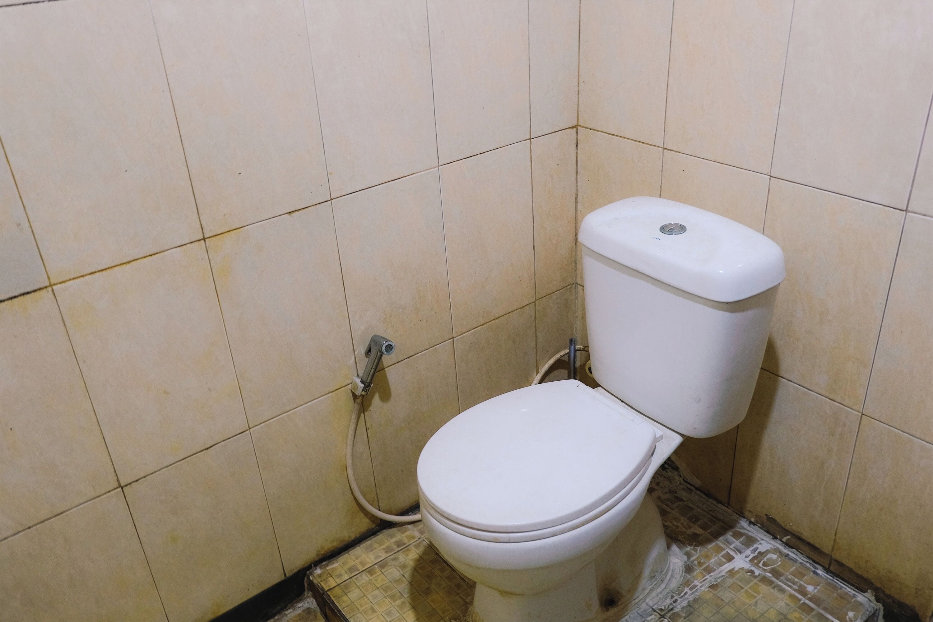 Un baño pequeño y sencillo con inodoro y una tubería a la vista.