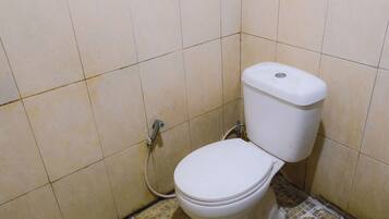 Un baño pequeño y sencillo con inodoro y una tubería a la vista.