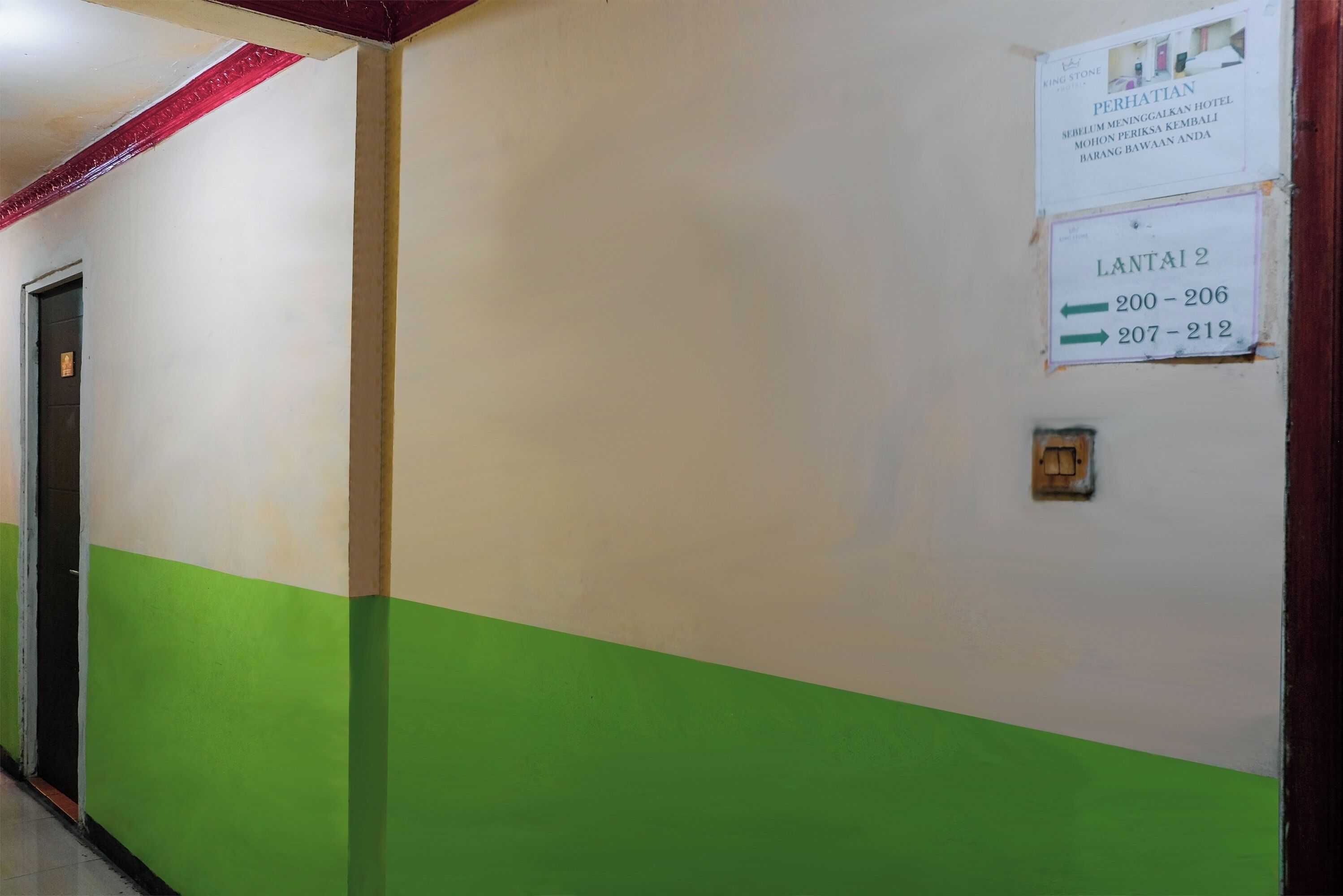 Un couloir aux murs verts et blancs, une porte sur la gauche et deux panneaux indiquant les numéros des chambres : 200 à 206 et 207 à 212.
