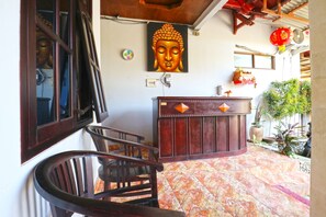 A reception area with a Buddha statue, a wooden reception desk, and a tiled floor. - Bangsal Homestay (Denpasar)