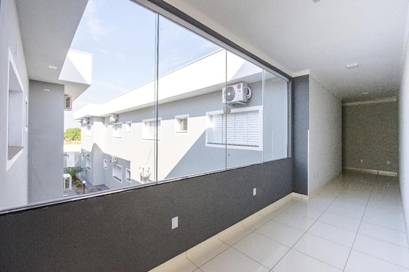 A modern apartment with large windows, a tiled floor, and a view of neighboring buildings. - Gabirá Hotel (Buritama)