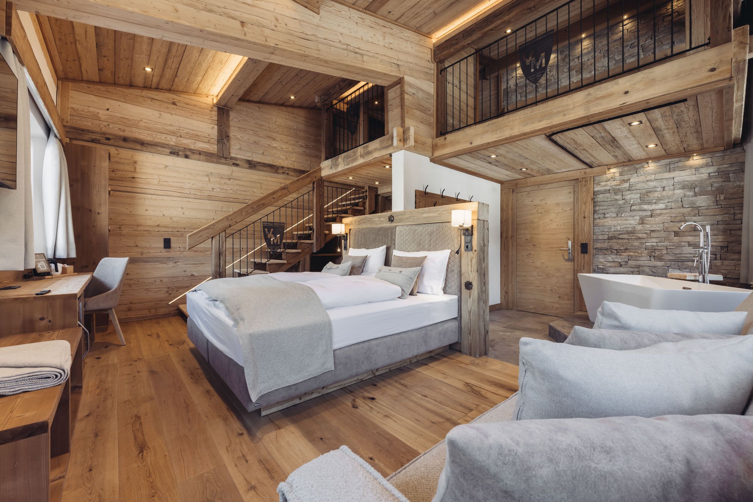 Un dormitorio amplio con una cama grande, una zona de estar con escritorio y un baño con bañera.